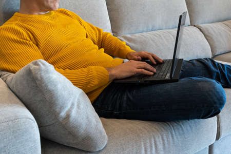 Man using a laptop sitting on the sofa. surfing the internet from home. Staying at homeの写真素材