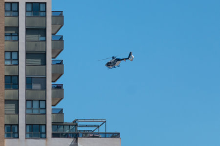Valencia, Spain - April 4, 2020: A National Police helicopter model Eurocopter EC-135 from Airbus company, hovers over residential buildingのeditorial素材