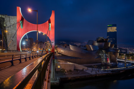 Bilbao, Spain - April 15, 2022: View of the NerviÃ³n river bank with the Guggenheim museum, the Iberdrola tower and the red arches of Daniel Buren from the La Salve bridge in Bilbao at nightのeditorial素材