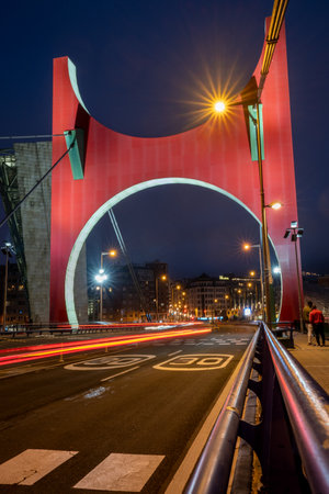 Bilbao, Spain - April 15, 2022: Traffic on La Salve Bridge with Daniel Buren's sculpture, Arcos Rojos in Bilbao, at night with car lights trailsのeditorial素材