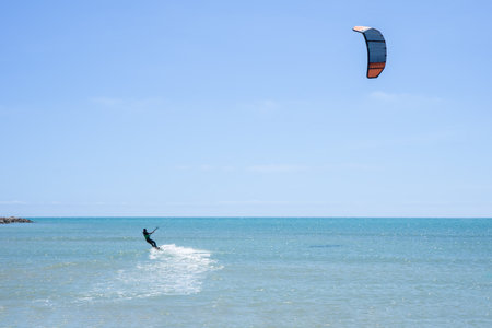 Rear view of a kitesurfer riding his kite in a calm sea. Water Sports Conceptの写真素材