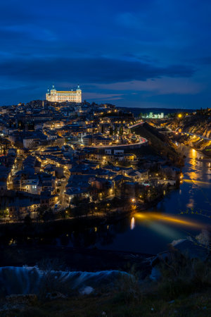 Vertical view of the historic center of Toledo, Spain, at night with the AlcÃ¡zar (now the army museum) illuminated and the Tagus River surrounding the city.の写真素材