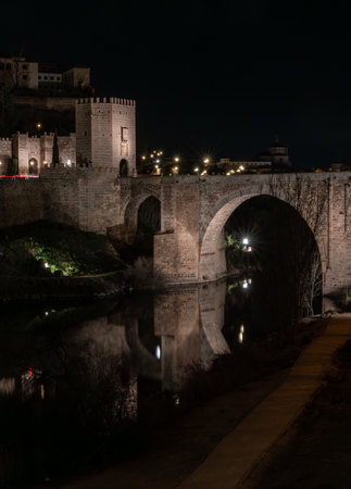 Alcantara Bridge with the tower at the entrance to the city and its reflection in the Tagus River in the middle of the night. Historical construction located in the city of Toledo, Spain.の写真素材