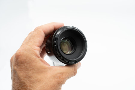 Valencia, Spain - August 8, 2021: Product photo. Close up image of a hand holding a Canon EF 50mm f/1.8 II photographic lens, showing it in detail on a white backgroundのeditorial素材