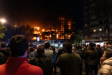Valencia, Spain - February 22, 2024: A group of people watch a large residential building fire from a distance in the city of Valencia, which quickly burns to the groundのeditorial素材