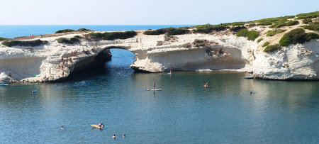 Natural arch in S'Archittu beach in Sardinia island, Italy with people enjoying a beach day. Summer tourism concept in Italyの写真素材