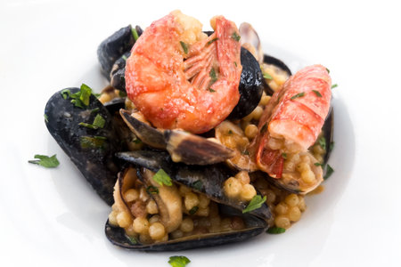 Typical seafood dish from the island of Sardinia (Italy) with fregola, a type of pasta from the area on a white background. Italian cuisine conceptの写真素材