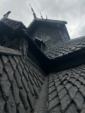 View from below of the wooden roof of the 12th century Norwegian Viking stave of Borgund, with medieval craftsmanship bellow a cloudy sky. Medieval Viking templeの写真素材