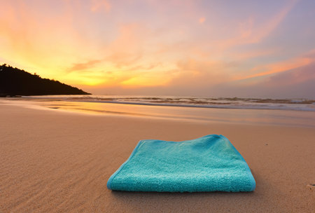 a towel in the sand on a beach at sunsetの写真素材