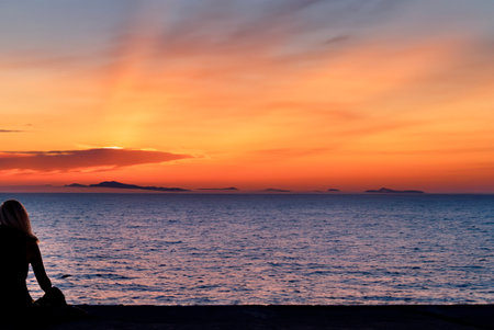 a woman watching a sunset on a torpical beach generated with artificial intelligenceの写真素材