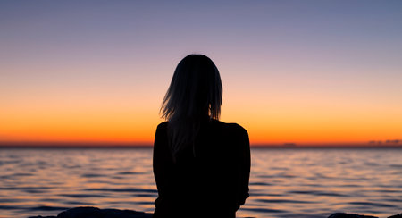 a woman watching a sunset on a tropical beachの写真素材