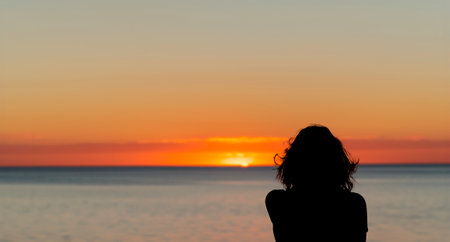 a woman watching a sunset on a torpical beach generated with artificial intelligenceの写真素材