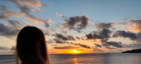 a woman watching a sunset on a tropical beachの写真素材