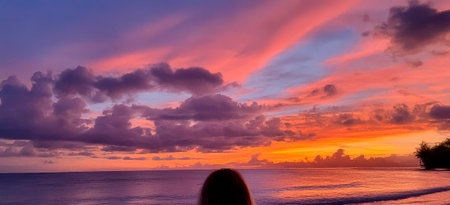 a woman watching a sunset on a tropical beachの写真素材