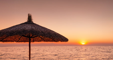 an umbrella on a beach at sunsetの写真素材
