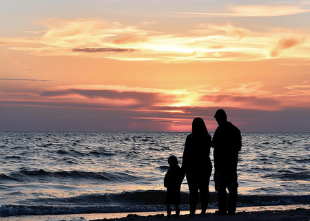 the silhouette of a family watching a sunset at the seaの写真素材