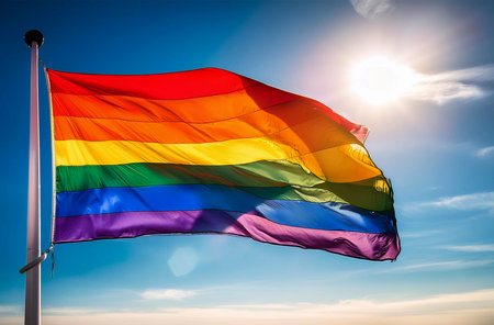 a gay pride flag waving in the blue sky