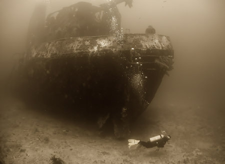 Artistic sepia photograph of a scuba diver exploring the interior of a shipwreck off the coast of Venezuela.の写真素材
