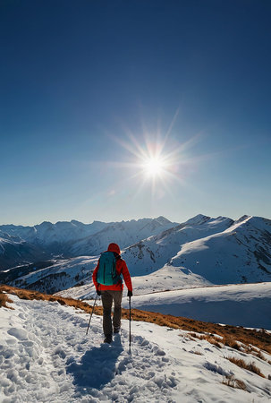 A lone hiker wearing a red jacket and backpack walks through a snowy trail surrounded by majestic...