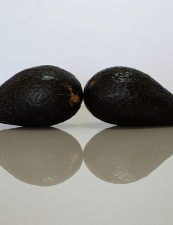 a group of avocados on a table with reflectionの写真素材