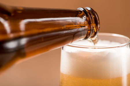 Beer pouring from top in bottle on wood tableの写真素材