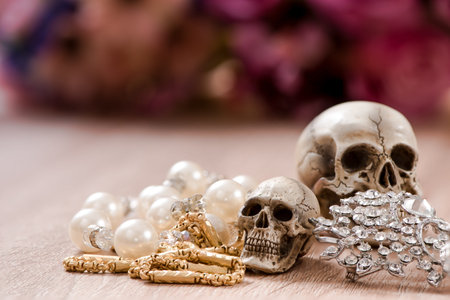 Still life with a human skull with old gold, diamond and jewelry and pearl necklaces standing on...