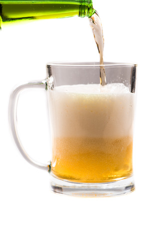glass of light beer pouring from bottle on a white backgroundの写真素材