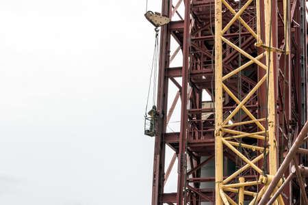 Welder welds metal parts at a heightの写真素材