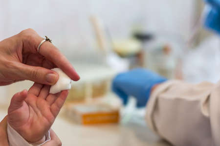 mother keeps a tampon on the child's finger after a blood capture in a medical officeの写真素材