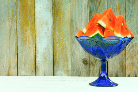 the water-melon sliced by triangular slices in a blue glass vaseの写真素材