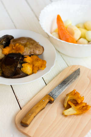 edible mushrooms, peeled potatoes, carrots, onions and knife on cutting Boardの写真素材
