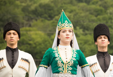 DAKHOVSKY, RUSSIA - JULY 25 2015: Muslims guys and the girl in national Adyghe suits against mountains. The Festival "Lago-Naki: Kunatskaya" was held in the mountains of Adygea in Dakhovsky, Russia, July 25 2015のeditorial素材