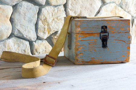 old wooden case on a tarpaulin belt near a stone wall closeup