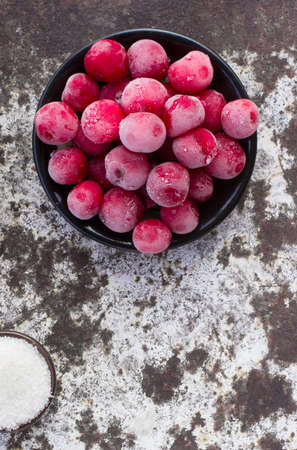 Frozen red cherries and white sugar on the peeled surface. Selective focus. Free space for text. Copy space.の写真素材