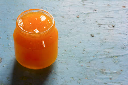 Small jar of honey on the blue background closeup. Free space for text. Copy spaceの写真素材