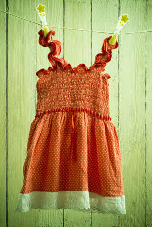 Old washed baby dress red with white polka dots hanging on the clothesline Toned photo. Retro, rustic styleの写真素材