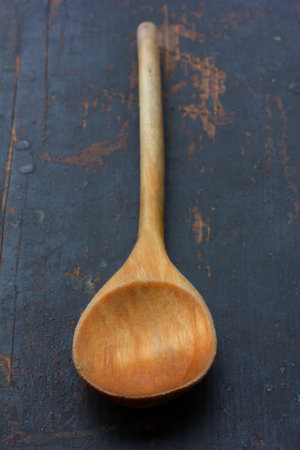 wooden kitchen spoon on an old black table, closeup, selective focus. rustic style