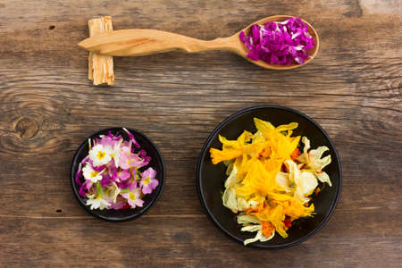 Fresh and dried flower petals in a wooden spoon on the old board. aromatherapy, herbal tea, homeopathic medicine.の写真素材