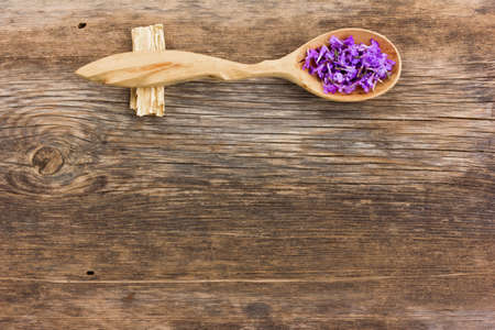 Fresh flower petals in a wooden spoon on the old board. aromatherapy, herbal tea, homeopathic medicine. Free space for text. Copy spaceの写真素材