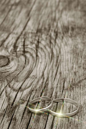 male and female wedding rings in gold with multicolor glare on an old cracked wooden board. selective focusの写真素材