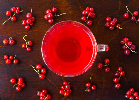 freshly squeezed red juice, and bunches of red currants on a brown wooden table with old paint. closeup flat layの写真素材
