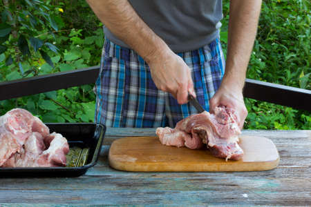 a white man cuts fresh pork meat on the background of nature. selective focusの写真素材