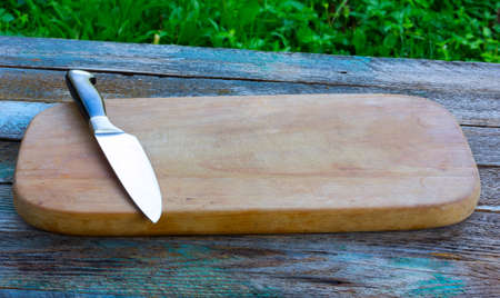 steel kitchen knife on an old cutting board on rustic wooden tableの写真素材