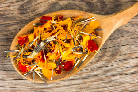 calendula petals in a wooden spoon on the old board was cracked. top view closeupの写真素材