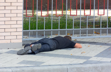 KRASNODAR, RUSSIA - AUGUST 4, 2016: a Drunk homeless man lying on the sidewalkのeditorial素材