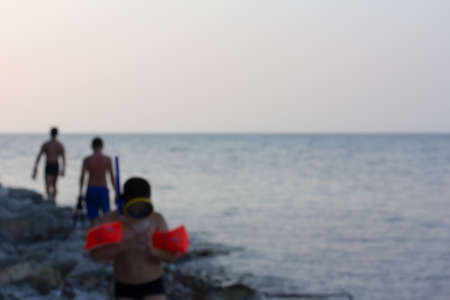 the blurred image of the sea shore with vacationers in the eveningの写真素材