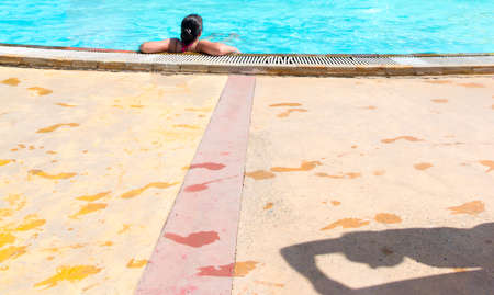 the girl in the pool, the shadow of a man and the wet footprints on the floor. selective focusの写真素材