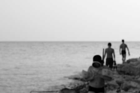 the blurred image of the sea shore with vacationers in the evening. black and white photoの写真素材