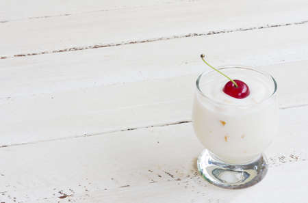 milk yogurt with berries cherries on white wooden backgroundの写真素材