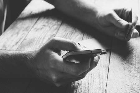 Man Hands holding credit card and using mobile phone in the evening. Online shopping, online banking and online marketing. shallow depth of field,  black and white toning photoの写真素材
